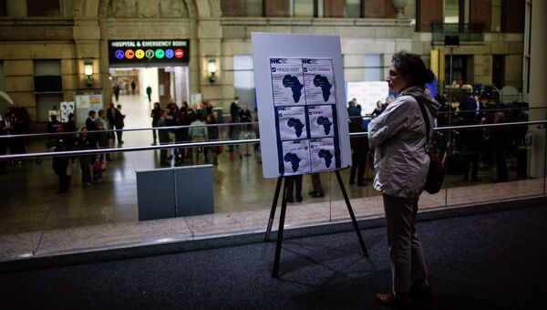 Женщина читает предупреждение об Эболе в госпитале в Нью-Йорке, где прохадит лечение врач Крейг Спенсер