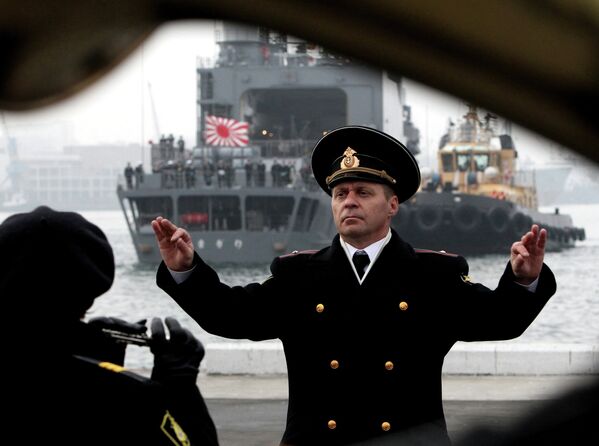 На переднем плане - дирижер оркестра тихоокеанского флота России играет по случаю прибытия эсминца Хамагири