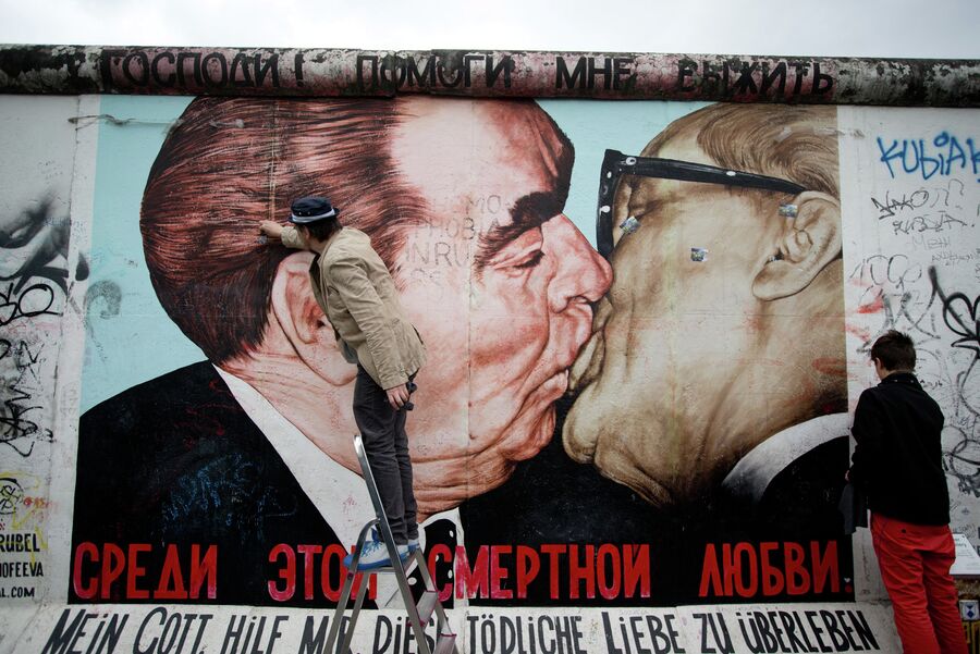 Художник Дмитрий Врубель с сыном очищают граффити расположенное на Берлинской стене