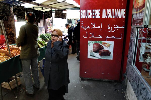 Покупательница проходит мимо мясной лавки с халяльными продуктами для мусульман на рынке в Париже Покупательница проходит мимо мясной лавки с халяльными продуктами для мусульман на рынке в Париже