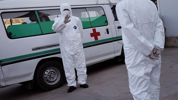 Медицинские сотрудники одетые в защитные костюмы в международном аэропорту Сунан в Пхеньяне