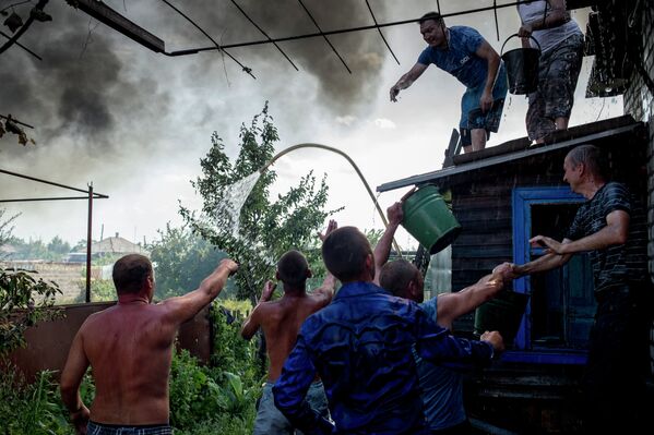 Местные жители во время тушения пожара в одном из домов в станице Луганская