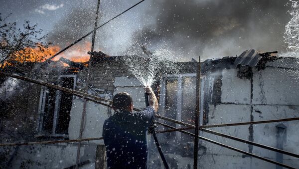 Мужчина тушит пожар в станице Луганская после авиаудара. Архивное фото