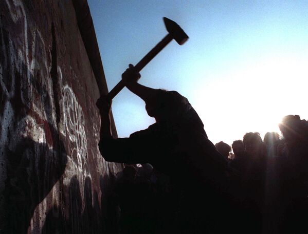 Человек бьет молотом по Берлинской стене