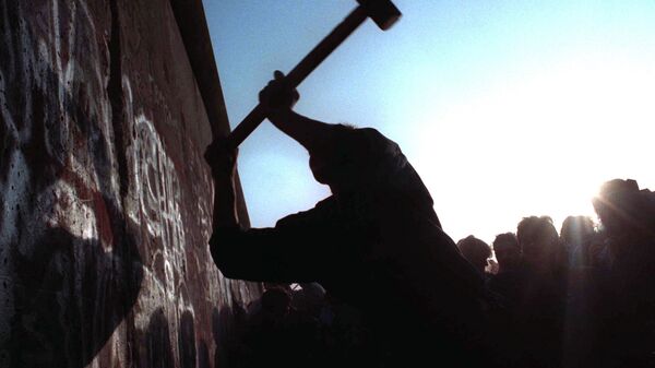 Человек бьет молотом по Берлинской стене. Архивное фото