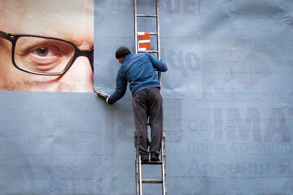 Рабочий прикрепляет портрет Арсения Яценюка на билборд в Киеве, Украина