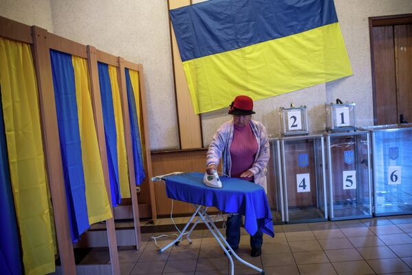 Женщина гладит шторку для кабинки для голосования в Киеве, Украина