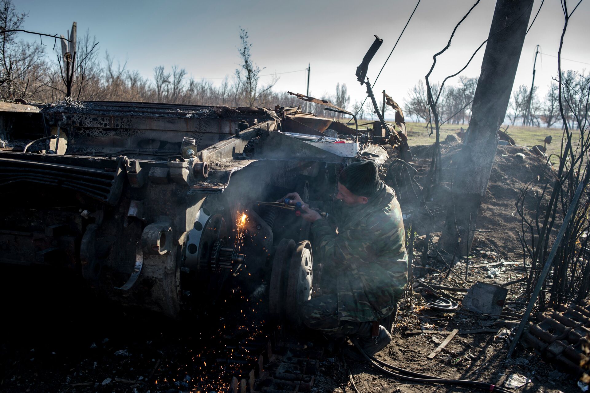 Боец ополчения ЛНР разбирает сгоревший украинский танк в поселке Новосветловка в Луганской области - РИА Новости, 1920, 03.05.2023