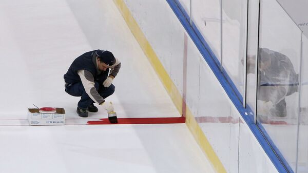 Строитель наносит разметку на лед хоккейного катка