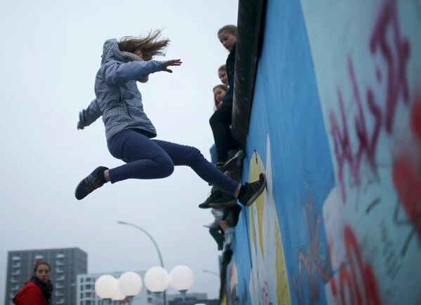 Участник проекта Цирк без границ прыгает на Берлинскую стену во время празднования 25-ой годовщины ее падения
