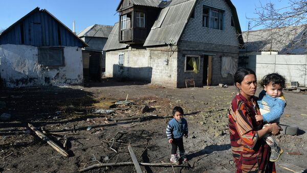 Женщина с детьми у своего дома, пострадавшего в результате артиллерийского обстрела