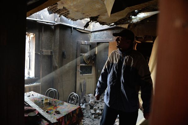 Мужчина в своем доме, разрушенном в результате артиллерийского обстрела