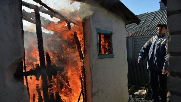Житель Донецка у своего дома, разрушенного и горящего после артиллерийского обстрела