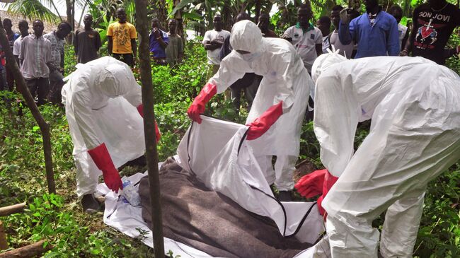 Сотрудники крематория эвакуируют тело человека, предположительно погибшего от вируса Эболы в Либерии