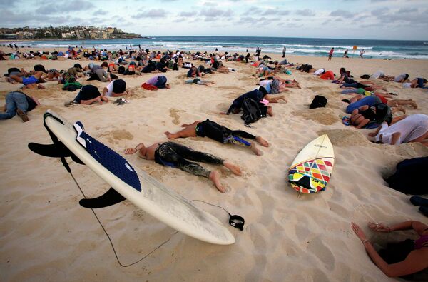 Группа из 400 демонстрантов приняла участие в акции протеста, пряча свои головы в песок на Сиднея Бонди Бич, Австралия