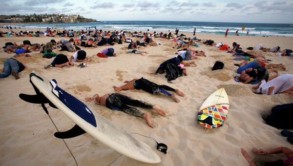 Группа из 400 демонстрантов приняла участие в акции протеста, пряча свои головы в песок на Сиднея Бонди Бич, Австралия