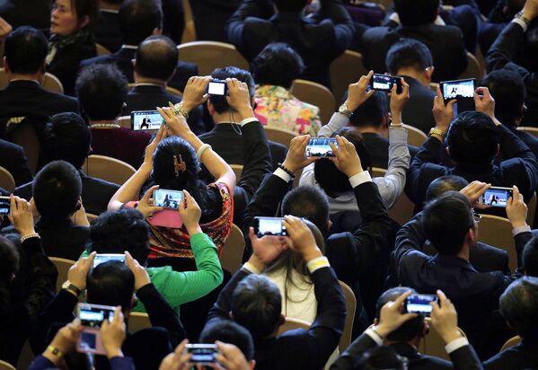 Гости Делового саммита форума АТЭС снимают на смартфоны выступление президента РФ Владимира Путина