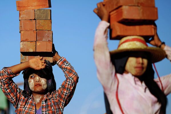 Рабочие стройки несут кирпичи в столице Мьянмы городе Нейпьидо