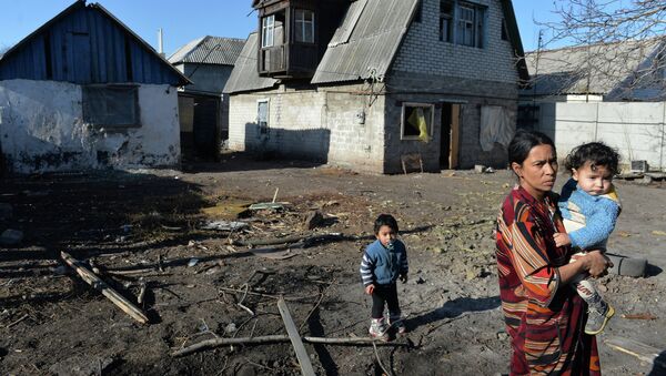 Женщина с детьми у своего дома, пострадавшего в результате артиллерийского обстрела украинскими силовиками города Донецка. Архивное фото