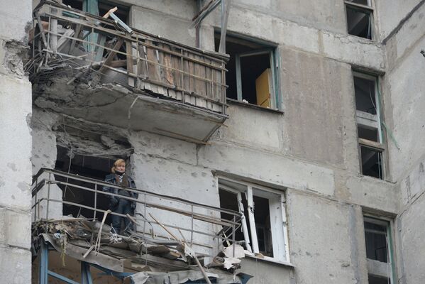 Женщина на балконе дома подвергшегося обстрелу украинскими военными