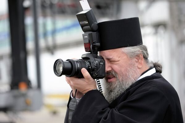 Священнослужитель фотографирует во время церемонии встречи патриарха Московского и всея Руси Кирилла