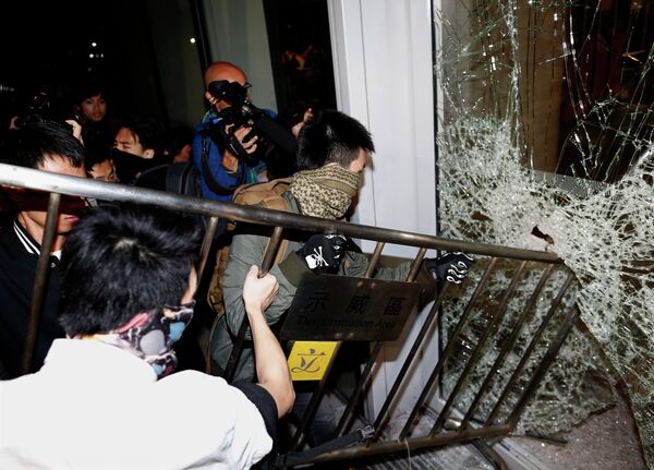 Протестующие пытаются выломать забором окно в здании Законодательного совета Гонконга