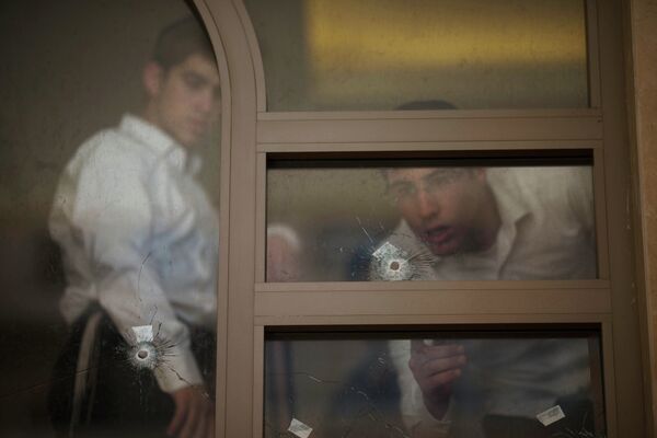 Юноши рассматривают пулевые отверстия после нападения на синагогу в Иерусалиме