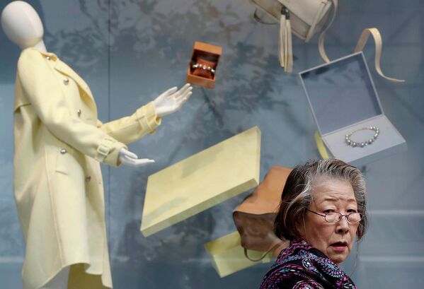 Женщина проходит мимо витрины одного из магазинов в торговом районе Токио, 16 ноября 2014