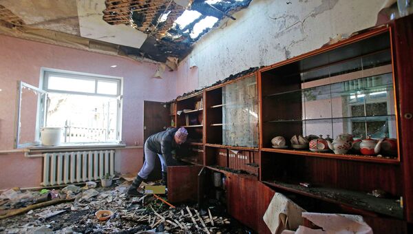 Женщина убирается в доме, поврежденном в результате обстрела в Донецке
