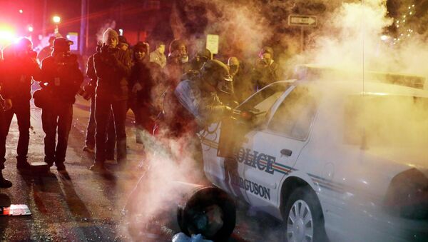 Сотрудник полиции стоит возле автомобиля, в который протестующие кинули дымовую шашку