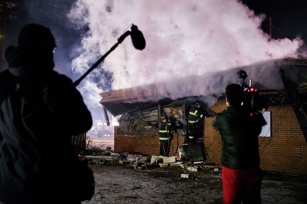Телеоператор снимает тушение пожара в здании, загоревшемся в результате беспорядков в Фергюсоне