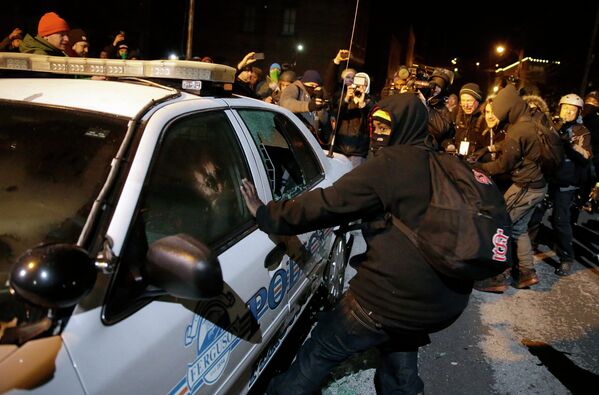 Протестующие разбивают полицейский автомобиль на улице города Фергюсон, США