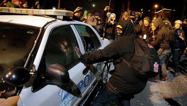 Протестующие разбивают полицейский автомобиль на улице города Фергюсон, США