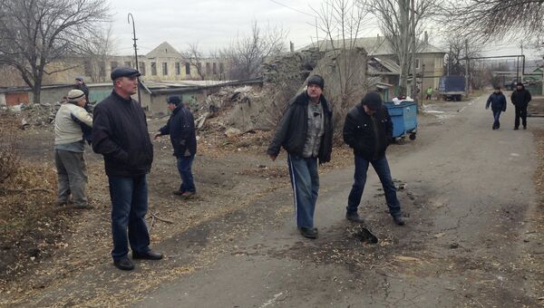 Жители микрорайона Азотный рассматривают осколок града после обстрела, в котором погибли 12-летний мальчик и 55-летняя женщина