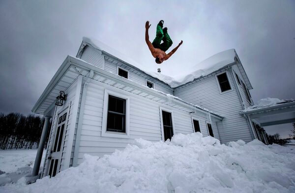 Мужчина прыгает в снег, после сильной метели в Нью-Йорке