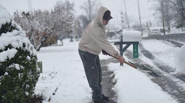 Мужчина очищает дорожку от снега в штате Пенсильвания, США. Архивное фото