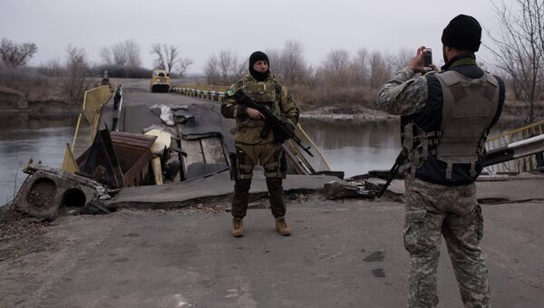 Украинские военные фотографируются на фоне разрушенного моста через реку Северский Донец. Архивное фото