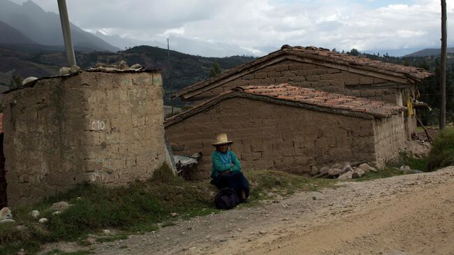 Пожилая женщина сидит возле дороги в Перу