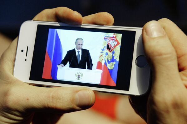 Житель Новосибирска смотрит на экране смартфона телевизионную трансляцию послания президента РФ Владимира Путина к Федеральному Собранию