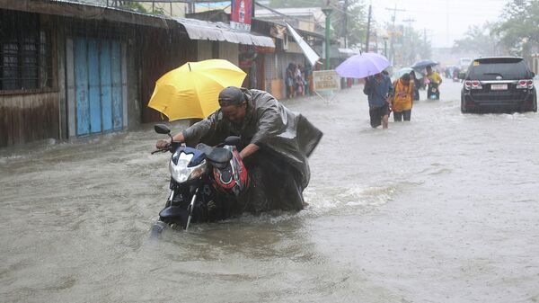 Люди на затопленной улице во время тайфуна Хагупит на Филиппинах