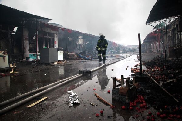 Пожарный идет мимо сожженных павильонов в центре Грозного.