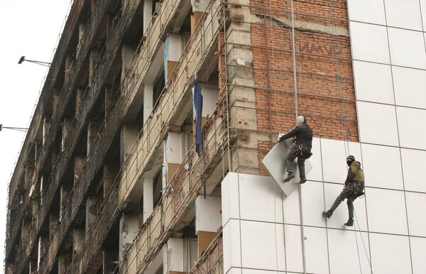Рабочие снимают для ремонта обшивку с Дома Печати в центре города Грозного