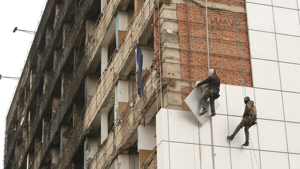 Рабочие снимают для ремонта обшивку с Дома Печати в центре города Грозного