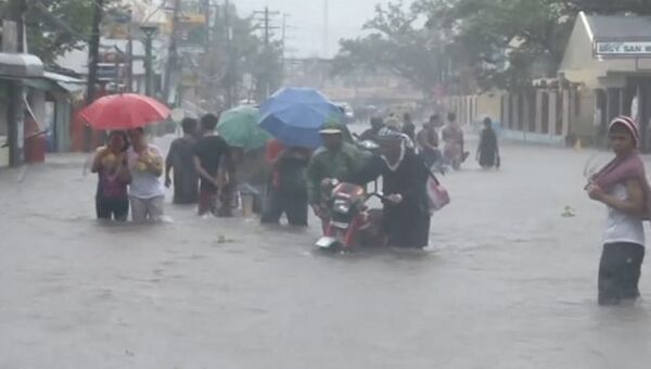 Люди передвигались по колено в воде из-за тайфуна Хагупит на Филиппинах