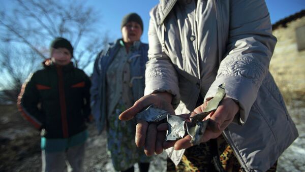 Женщина показывает осколки снаряда после обстрела микрорайона Азотный в Донецке