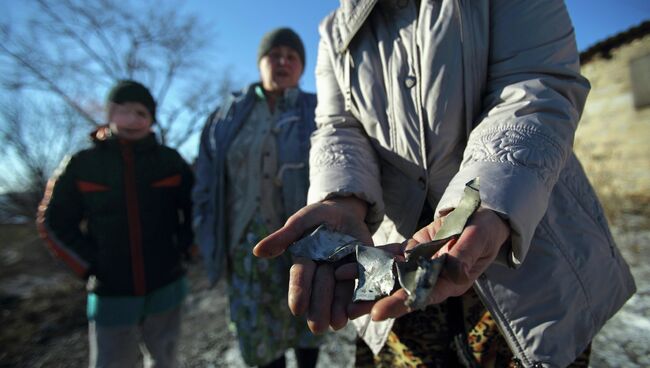 Женщина показывает осколки снаряда после обстрела микрорайона Азотный в Донецке