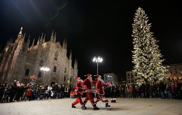 Мужчины в костюмах Санта-Клаусов перед готическим собором Дуомо в Милане, Италия