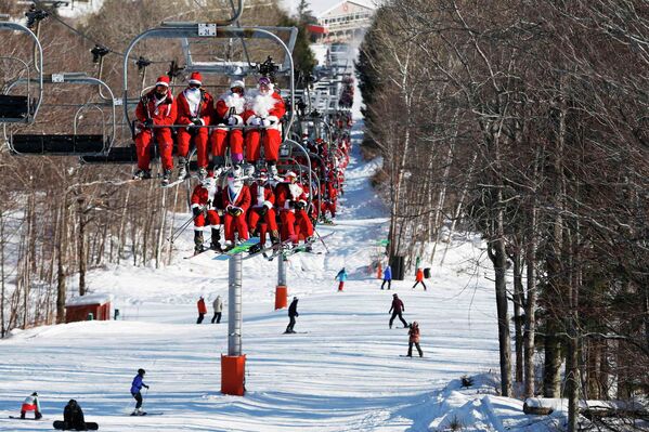 Люди в костюмах Санта-Клауса перед началом благотворительного забега по горнолыжному склону в штате Мэн, США