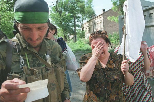 Чеченский боевик проверяет бумаги женщины идущей в Грозный