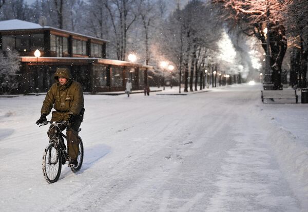 Человек едет на велосипеде во время снегопада в Москве
